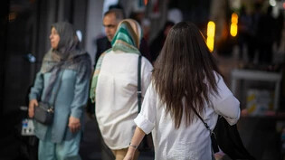 ARCHIV - Eine Frau läuft in Teheran mit offenen Haaren am Abend eine Straße entlang. Eine Kommission des Parlaments hat das umstrittene neue Kopftuchgesetz überarbeitet. Der Gesetzentwurf sei erneut dem sogenannten Wächterrat, einem erzkonservativen…