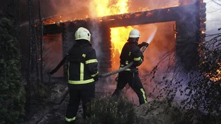 Feuerwehrleute löschen ein Feuer, nachdem ein Haus von russischem Beschuss getroffen wurde. Foto: Andrii Marienko/AP/dpa