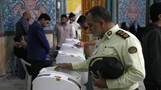 Ein iranischer Polizeioberst gibt in einem Wahllokal seinen Wahlzettel für die parlamentarische Stichwahl ab. Foto: Vahid Salemi/AP