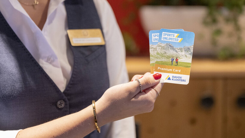Kleine Karte, grosses Potenzial: Eine Hotelfachfrau präsentiert zwei Gästekarten der Tourismusdestination Davos Klosters.