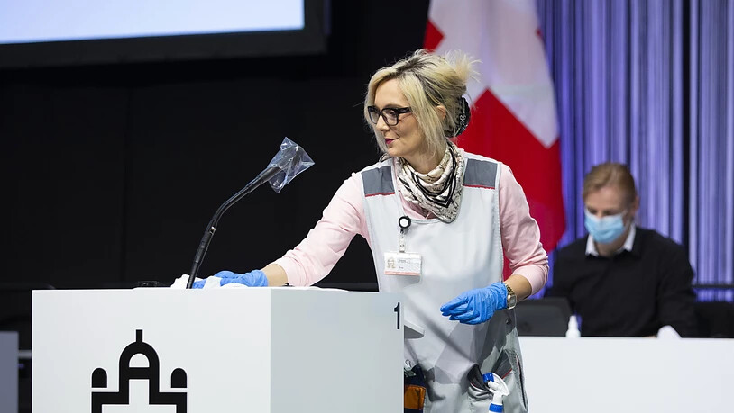 Ana Steko, Mitarbeiterin beim Bundesamt für Bauen und Logistik (BBL), desinfiziert ein Rednerpult während der ausserordentlichen Session der Eidgenössischen Räte in einer Ausstellungshalle der Bernexpo in Bern.