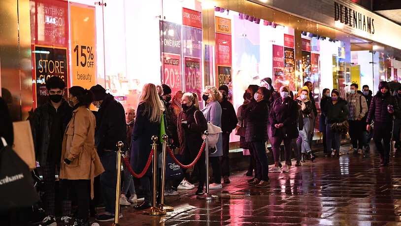 Menschen stehen am letzten Samstag vor Weihnachten auf der Oxford Street in London vor einem Geschäft Schlange. Foto: Stefan Rousseau/PA Wire/dpa