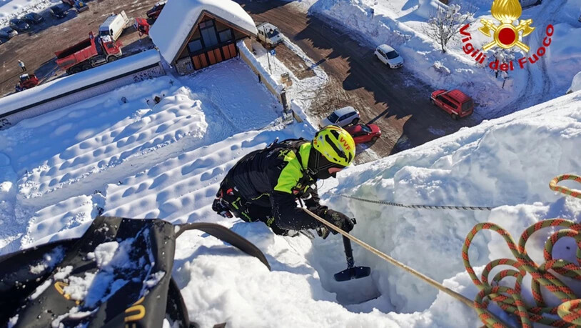 HANDOUT - Ein Feuerwehrmann hilft bei der Schneeräumung und -sicherung auf dem Dach der Kirche Santa Margherita in dem Dorf in der nordöstlichen Region Friaul-Julisch Venetien. Kräftige Schneefälle haben der Feuerwehr in Italien zahlreiche Einsätze…