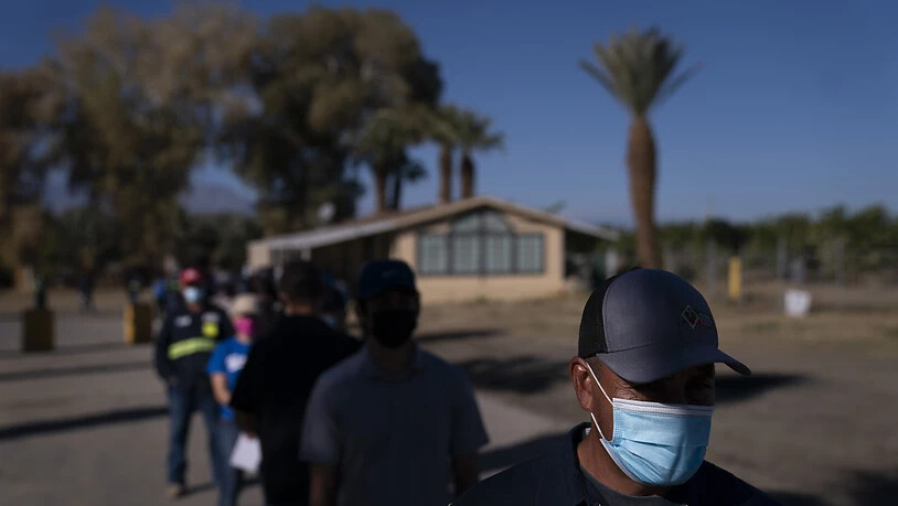 Eingewanderte Landarbeiter tragen Mund-Nasen-Bedeckungen und warten in einer Schlange, um die Corona-Impfung zu erhalten. Verbände warnen davor, dass Millionen Einwanderer zu den am schwierigsten zu erreichenden Menschen während der größten Impfkampagne…