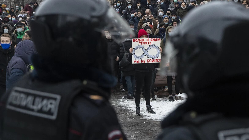 Eine Frau hält gegenüber von Polizisten ein Schild mit Porträts des russischen Präsidentens Putin und der Aufschrift «Wir werden es nicht mehr hinnehmen! Wir haben keine Angst». Foto: Pavel Golovkin/AP/dpa