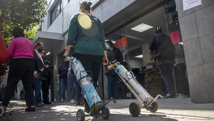 Eine Frau bringt zwei Sauerstoffflaschen zu einem Laden, in dem diese nachgefüllt werden sollen. Foto: Jair Cabrera Torres/dpa