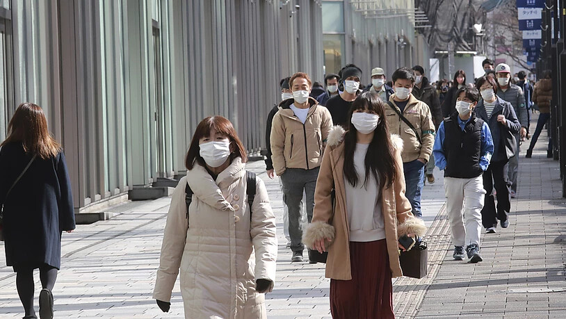 Passanten tragen Schutzmasken und gehen einen Bürgersteig in Tokio entlang. Foto: Koji Sasahara/AP/dpa