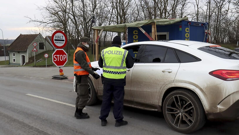 Ein Soldat der österreichischen Armee und ein Polizist kontrollieren einen Autofahrer nach der Grenzüberquerung von Tschechien nach Österreich. Österreich hat die Einschränkungen zur Eindämmung der Corona-Pandemie verschärft. Foto: Ronald Zak/AP/dpa