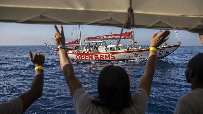 ARCHIV - Migranten winken an Deck des Rettungsschiffs "Open Arms", das sich dem Hafen von Barcelona nähert. Foto: Olmo Calvo/AP/dpa