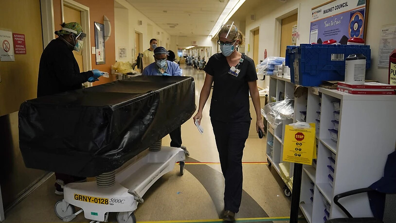 Die Geistliche Kristin Michealsen (r) verlässt eine Corona-Station im Krankenhaus «Providence Holy Cross Medical Center», nachdem sie mit einem Familienmitglied eines verstorbenen Patienten gesprochen hat, während Transporteure eine Trage mit der Leiche…