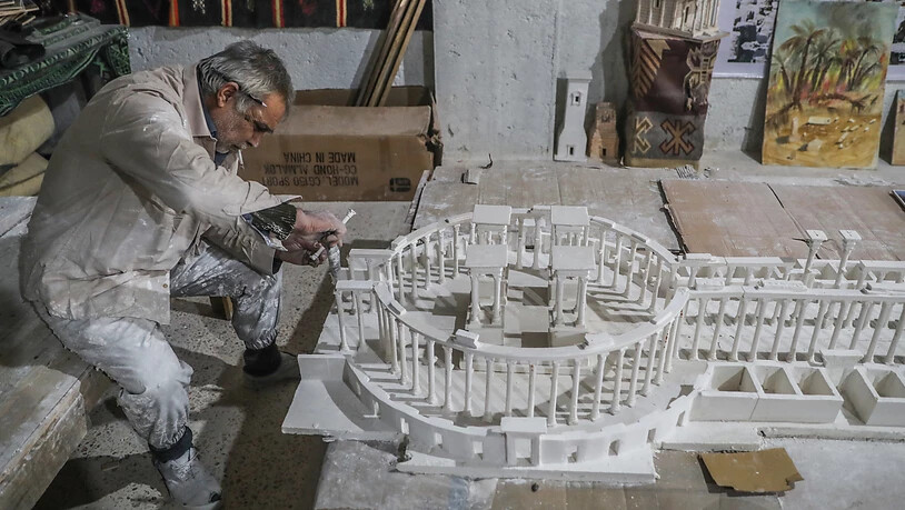Ali Alsaleh in seiner Werkstatt bei der Arbeit an seinem Modell der antiken Oasenstadt Palmyra. Foto: Anas Alkharboutli/dpa