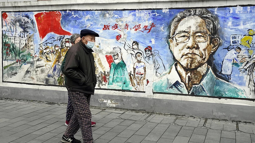 Anwohner gehen in der zentralchinesischen Stadt Wuhan, in der das Coronavirus zum ersten Mal nachgewiesen wurde, an einem Wandgemälde mit dem Titel «Erinnerungen» vorbei. Foto: Ng Han Guan/AP/dpa