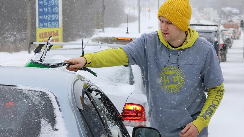 Ein Mann wischt bei Schneefall Schnee von einem Auto auf der Dmitrovskoye-Autobahn. Nach stundenlangen starken Schneefällen und -stürmen steuert die russische Hauptstadt Moskau auf eine Rekordschneedecke zu. Foto: Vladimir Gerdo/TASS/dpa