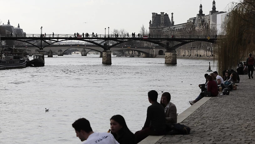 Menschen am Ufer der Seine in Paris. Foto: Lewis Joly/AP/dpa