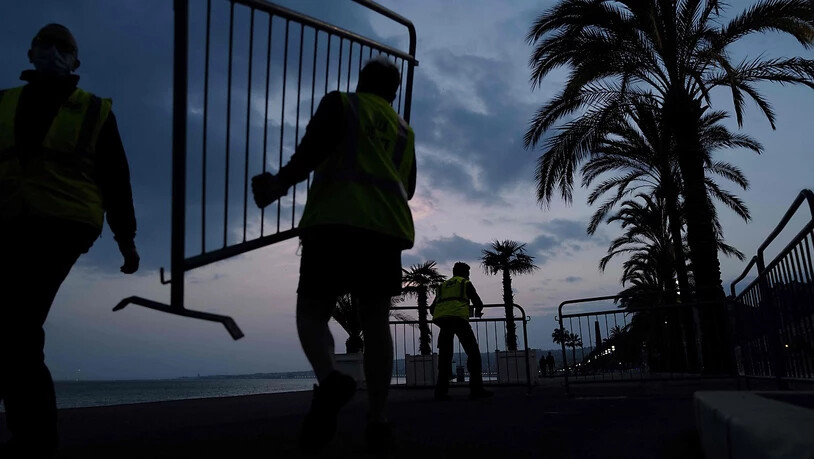 dpatopbilder - Ein Angestellter der Stadt Nizza trägt einen Absperrzaun, um die Promenade des Anglais am Vorabend der coronabedingten Wochenendabriegelung für die Öffentlichkeit abzusperren. Foto: Valery Hache/AFP/dpa