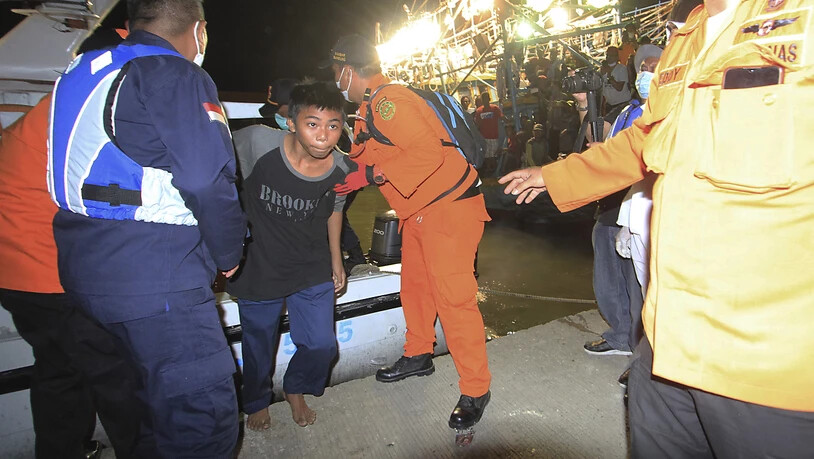 Rettungskräfte helfen einem der Überlebenden des Schiffsunglücks bei seiner Ankunft im Hafen von Indramayu. Foto: Panji Wisnu/AP/dpa