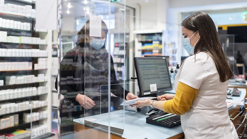 Eine Mitarbeiterin der Apotheke Stadelhofen übergibt die fünf gratis Antigen-Schnelltests an eine Kundin.