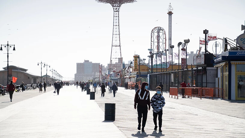ARCHIV - Passanten mit Mundschutzen spazieren die Strandpromenade von Coney Island in New York entlang. Foto: Braulio Jatar/SOPA Images via ZUMA Wire/dpa