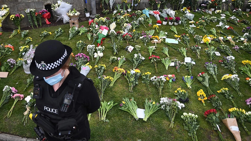 dpatopbilder - Eine Polizistin steht vor einer Grünfläche vor Schloss Windsor, auf der Blumen für den verstorbenen Philip abgelegt wurden. Foto: Victoria Jones/PA Wire/dpa