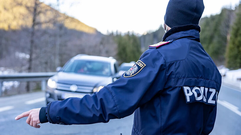 Ein Polizist kontrolliert Fahrzeuge auf einer Straße nahe Kitzbühel. Tirol verlängert die Pflicht zu Corona-Ausreisetests. Foto: Expa/Johann Groder/APA/dpa