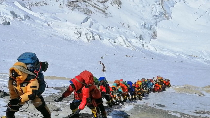 ARCHIV - In einer langer Schlange klettern Bergsteiger auf einem Pfad knapp unterhalb von Lager vier. Trotz Pandemie gibt es auf dem Mount Everest einen Besucherrekord. Foto: Rizza Alee/AP/dpa
