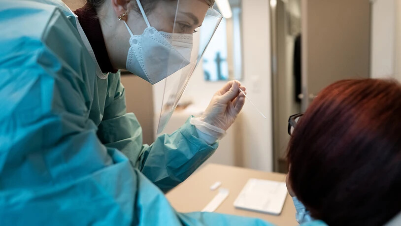 Eine Apothekerin in Schutzkleidung macht bei einer Frau einen Abstrich für einen Covid-19 Antigen-Schnelltest. (Archivbild)