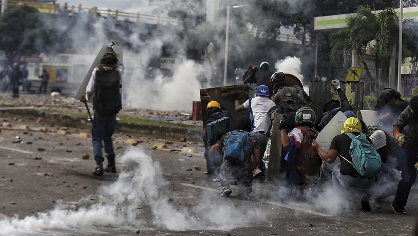 Demonstranten stoßen während eines nationalen Streiks gegen die Steuerreform mit der Polizei zusammen. Kolumbiens Präsident Duque hatte zuvor die von der Regierung vorgeschlagene Steuerreform zurückgezogen. Foto: Andres Gonzalez/AP/dpa