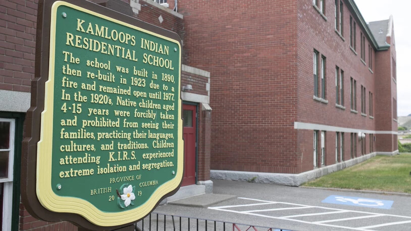 Eine Gedenktafel ist außerhalb der ehemaligen Kamloops Indian Residential School zu sehen. Überreste von 215 Kindern kanadischer Ureinwohner sind auf einem Grundstück einer sogenannten Residential School in Kanada entdeckt worden. Sie seien bei Radar…