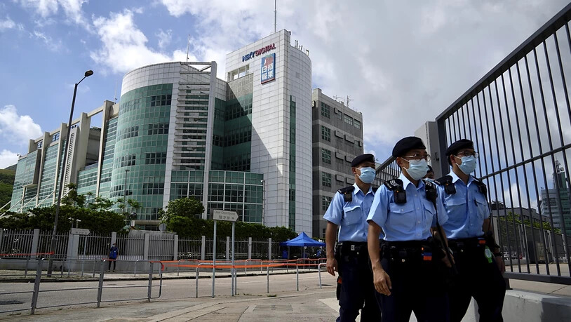 Polizisten gehen vor dem Hauptquartier der pro-demokratischen Zeitung Apple Daily. Fünf Führungskräfte der pro-demokratischen Hongkonger Zeitung «Apple Daily» sind am Donnerstag wegen angeblicher Verstöße gegen das umstrittene Sicherheitsgesetz…