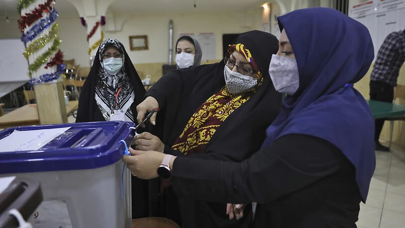 Wahlhelferinnen öffnen eine Wahlurne in einem Wahllokal. Foto: Vahid Salemi/AP/dpa