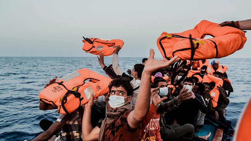 HANDOUT - Ein Helfer reicht den Bootsmigranten in einem kleinen Boot Rettungswesten. Foto: Flavio Gasperini/SOS Mediterranee/dpa - ACHTUNG: Nur zur redaktionellen Verwendung im Zusammenhang mit der aktuellen Berichterstattung und nur mit vollständiger…