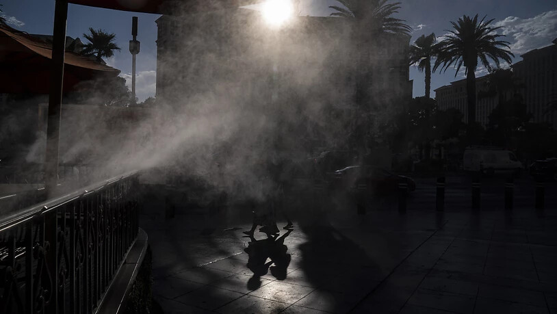 dpatopbilder - Menschen gehen in Las Vegas an Nebelmaschinen vorbei, die zur Abkühlung entlang des Las Vegas Strip eingesetzt werden. Las Vegas könnte an diesem Wochenende sein Temperatur-Allzeithoch erreichen, da für den Bundesstaat und große Teile der…