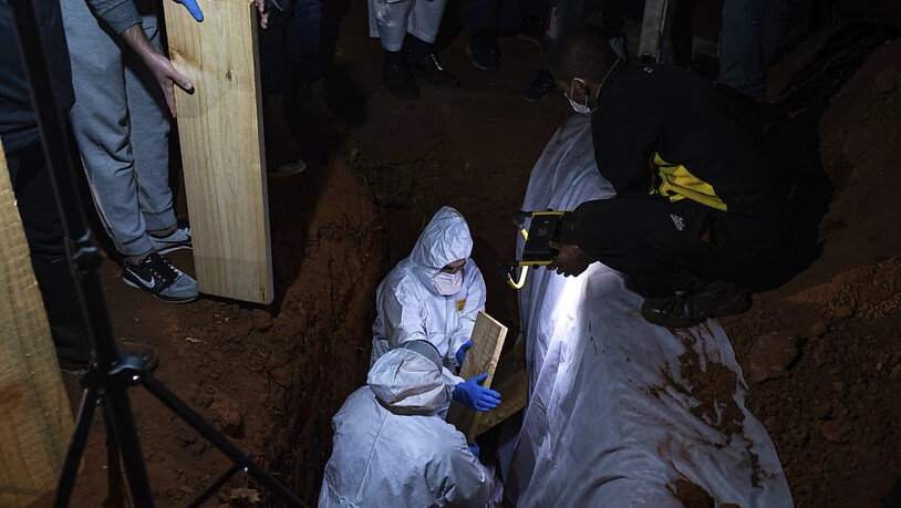 dpatopbilder - Menschen in Schutzkleidung nehmen in Johannesburg an einer Beerdigung einer an Corona gestorbenen Person teil. Südafrika ist eines der Länder auf dem Kontinent mit den meisten Todesfällen in Zusammenhang mit dem Coronavirus. Foto: Ali…