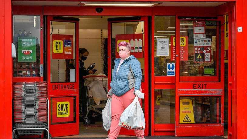 ARCHIV - Eine Frau mit Mundschutz verlässt einen Supermarkt im britischen Caerphilly. Foto: Ben Birchall/PA Wire/dpa