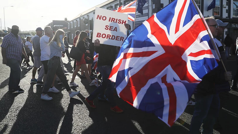 ARCHIV - Demonstranten halten britische Fahnen und ein Schild mit der Aufschrift «No Irish Sea Border» («Keine irische See-Grenze») bei einem Protest protestantischer Loyalisten gegen das sogenannte Nordirland-Protokoll. Foto: Brian Lawless/PA Wire/dpa