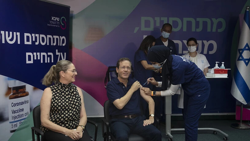 Izchak Herzog (M), Staatspräsident von Israel, erhält eine dritte Impfung gegen das Coronavirus, während seine Frau Michal (l) zusieht. Foto: Maya Alleruzzo/POOL AP/dpa
