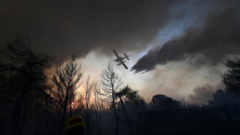 Ein Flugzeug wirft über einem Waldbrand nördlich von Athen Löschwasser ab. Foto: Michael Varaklas/AP/dpa