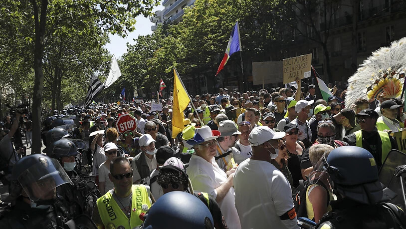 Demonstranten halten Fahnen und Schilder bei einem Protest gegen die Corona-Regeln. Der Unmut der Demonstranten richtet sich gegen die Impfpflicht für Gesundheitspersonal und gegen jüngst von der französischen Regierung beschlossene verschärfte…