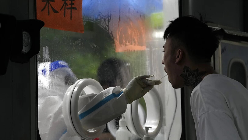 Ein Arbeiter nimmt in einer Sammelstelle in Peking eine Abstrichprobe für einen COVID-19-Test ab. Foto: Ng Han Guan/AP/dpa