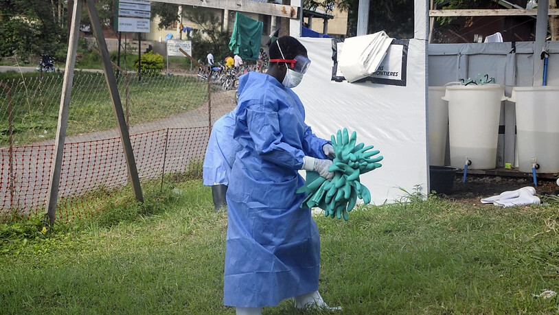 ARCHIV - Ein Mitarbeiter in medizinischer Schutzkleidung trägt Schutzhandschuhe in einem Krankenhaus, in dem ein Ebola-Opfer isoliert wurde. Foto: Ronald Kabuubi/AP/dpa