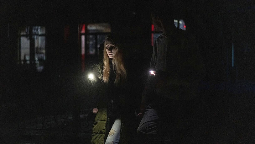 dpatopbilder - Ein junges Paar spaziert durch das Stadtzentrum, das nach einem russischen Raketenangriff am Tag zuvor ohne Strom ist. Foto: Evgeniy Maloletka/AP/dpa