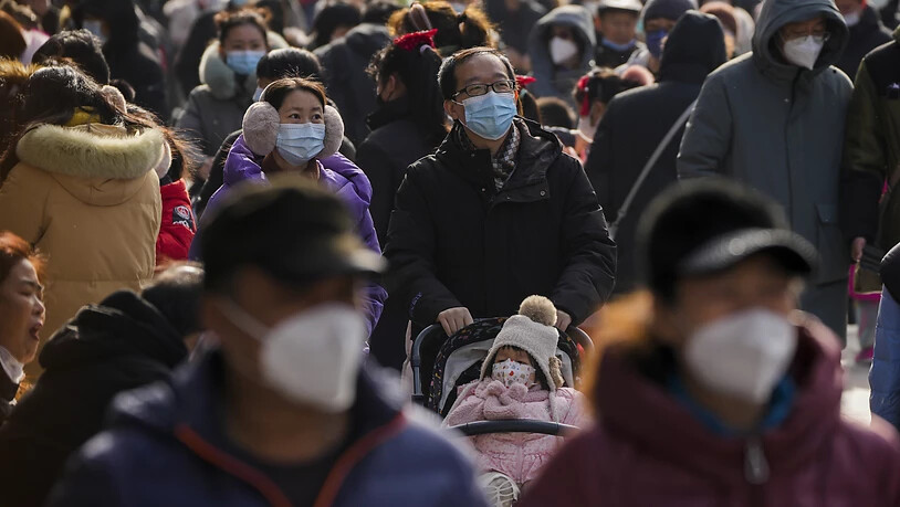 Besucher mit Gesichtsmasken spazieren am ersten Tag des Mondneujahrsfestes in Peking durch die Fußgängerzone Qianmen. Foto: Andy Wong/AP/dpa