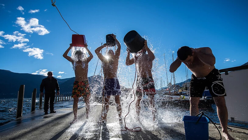 Um beim Dreikönigsschwimmen in Brissago TI weniger zu frieren, leeren sich diese Teilnehmer bereits vor dem Start kaltes Wasser über den Kopf. (Archivbild)
