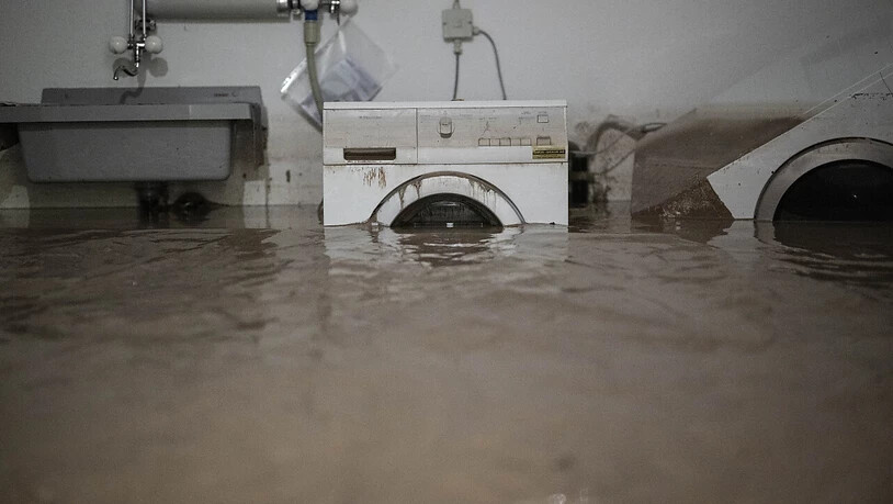 Eine Waschmaschine steht in einem Haus im Schlamm. Der Zivilschutz soll die Gebäude wieder freiräumen.
