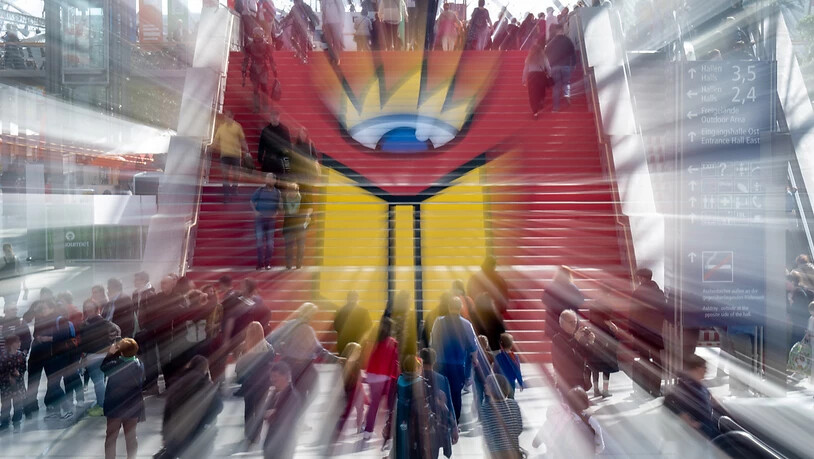 ARCHIV - Besucherinnen und Besucher gehen über eine Treppe mit dem Logo der Leipziger Buchmesse. Foto: Hendrik Schmidt/dpa