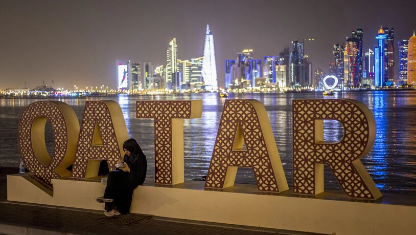 Eine Frau isst vor der Skyline von Doha.