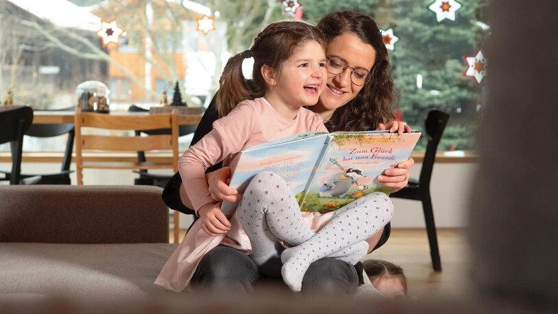 Die Mutter Flurina Eschmann liest mit ihrer Tochter Adriana vergnügt ein Buch: Der kleine Sonnenschein Adriana ist trotz der seltenen Krankheit Tatton-Brown-Rahman-Syndrom ein fröhliches Kind.