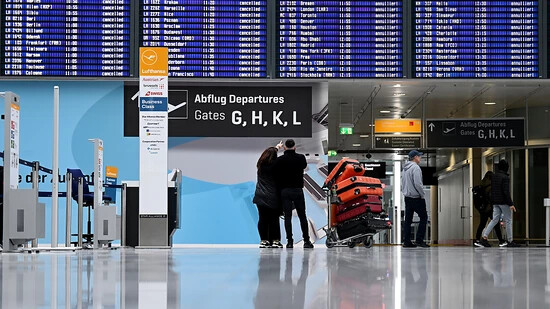 ARCHIV - Passagiere stehen im Münchner Flughafen vor der Anzeigentafel. Wegen eines angekündigten Eisregens wird es am Münchner Flughafen am Dienstag von Betriebsbeginn bis 12.00 Uhr keine Starts und Landungen geben. Foto: Angelika Warmuth/dpa