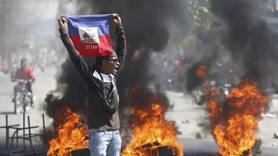 dpatopbilder - Ein Demonstrant hält eine haitianische Flagge während Protesten für den Rücktritt von Premierminister Henry hoch. Foto: Odelyn Joseph/AP
