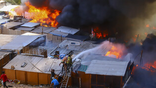 Nachbarn helfen Feuerwehrleuten bei der Bekämpfung eines Brandes in dem einkommensschwachen Viertel Laguna Verde in Iquique, im Norden von Chile. Bei dem Großbrand sind mindestens 100 Häuser zerstört worden und mehr als 400 Menschen obdachlos geworden,…
